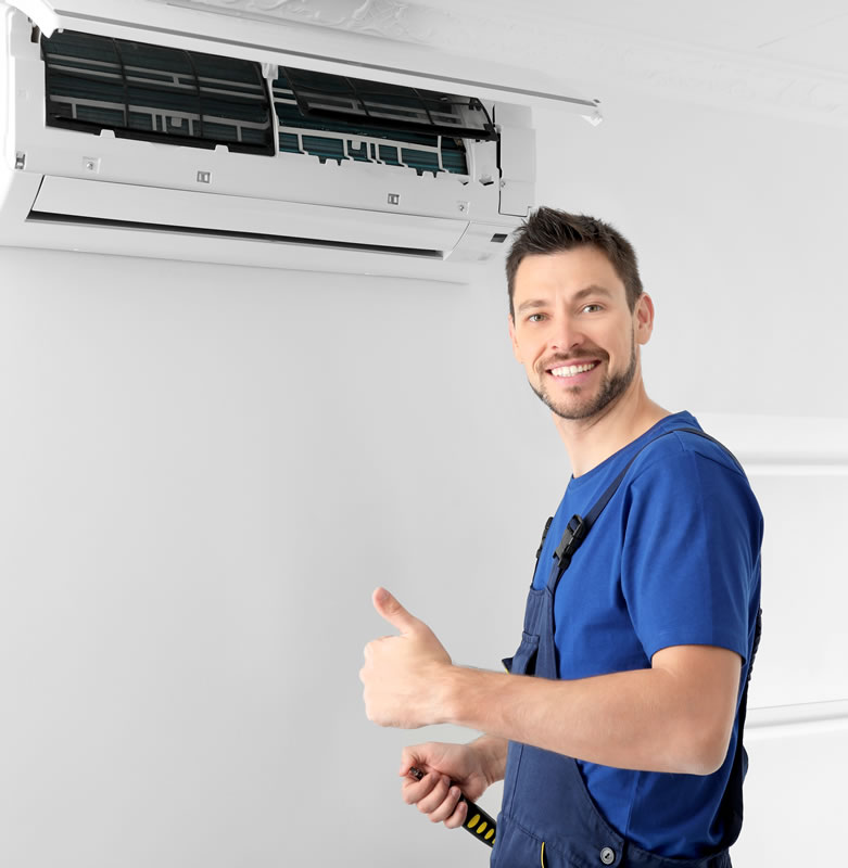 Man looking at camera standing next to wall mounted air con unit